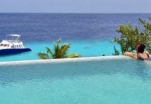 Toerist staart naar de zee in een overloopzwembad op Curaçao.